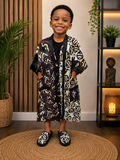 Young child wearing an African-inspired kimono robe with matching slippers in black, cream, and maroon print.